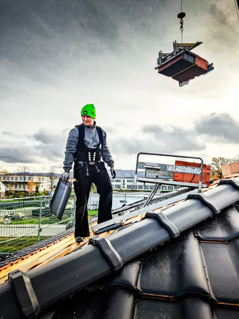 Arbeiter mit Dachziegel in der Hand auf dem Dach